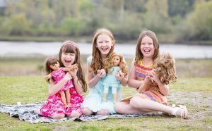 Foto de tres niñas aprendiendo a jugar con muñecas